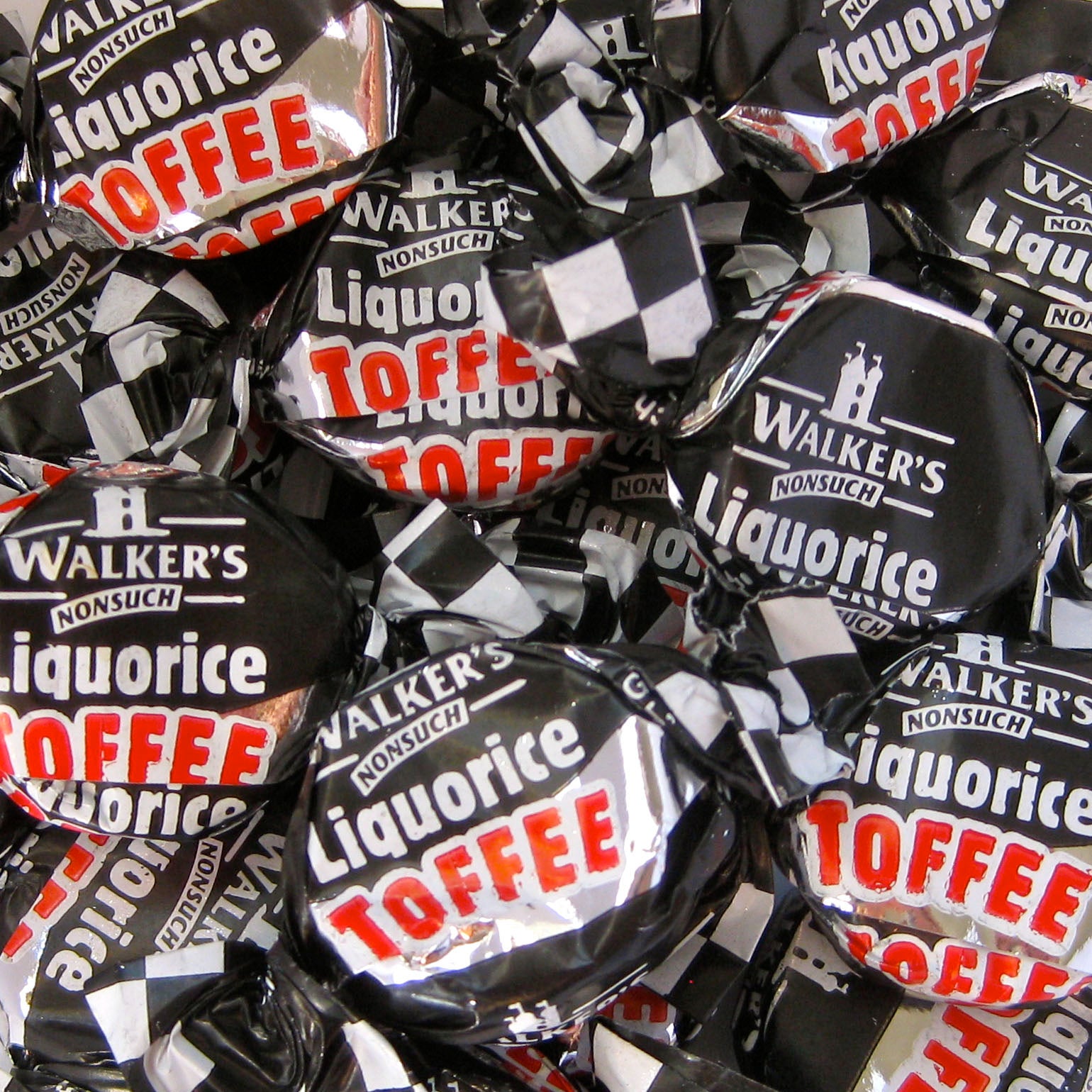 Individual pieces of Walkers Liquorice Toffee in distinctive black foil wrappers.